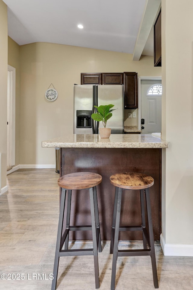 2503 Twin Oaks Ln, Port Royal, SC 29935 - kitchen with stainless steel fridge with ice dispenser, dark brown cabinetry, a breakfast bar area, light wood-style floors, and baseboards