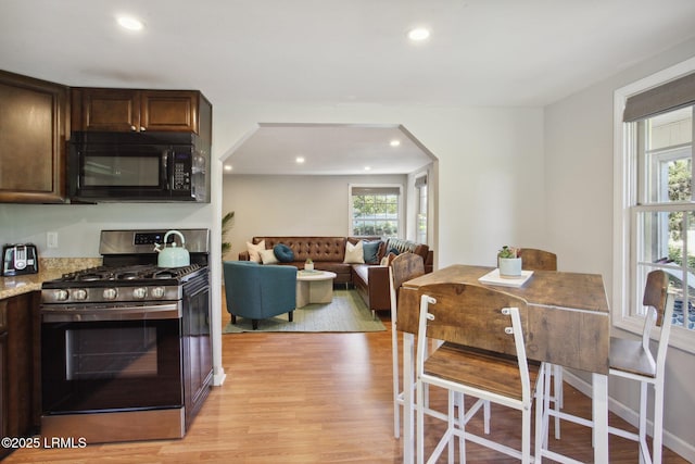 2503 Twin Oaks Ln, Port Royal, SC 29935 - kitchen with black microwave, stainless steel gas stove, light wood-style flooring, recessed lighting, and arched walkways