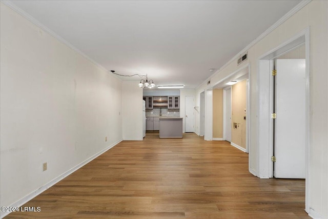 unfurnished living room featuring crown molding, hardwood / wood-style floors, and an inviting chandelier