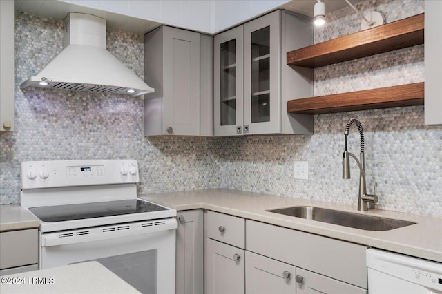 kitchen with wall chimney exhaust hood, sink, gray cabinets, white appliances, and decorative backsplash