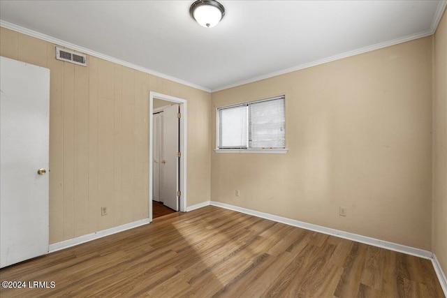 unfurnished bedroom with wood-type flooring, ornamental molding, and a closet