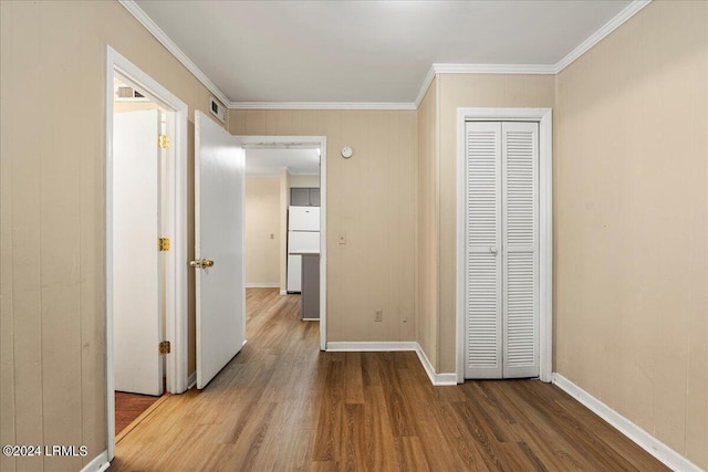 unfurnished bedroom featuring white refrigerator, ornamental molding, hardwood / wood-style floors, and a closet