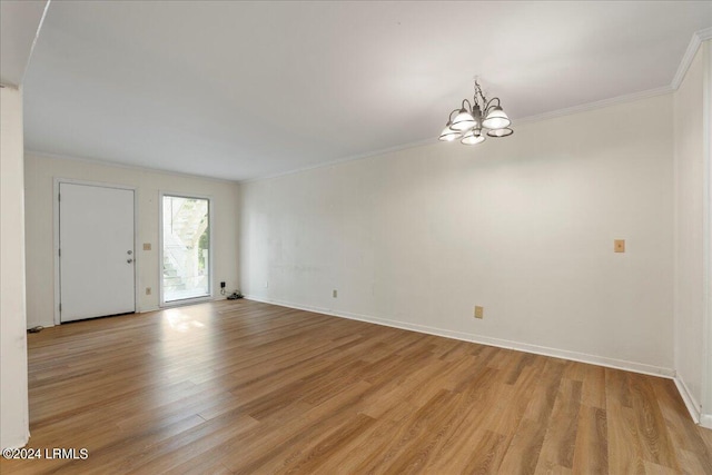 empty room featuring an inviting chandelier, crown molding, and light wood-type flooring