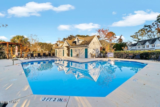 pool with a patio area, fence, and a residential view