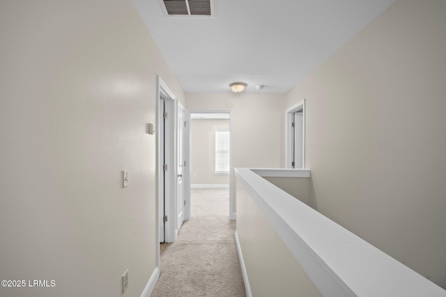 hallway with baseboards, an upstairs landing, visible vents, and light colored carpet