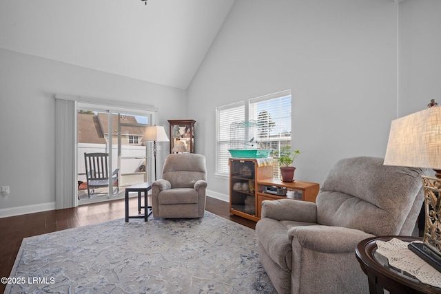 living area with high vaulted ceiling, plenty of natural light, baseboards, and wood finished floors