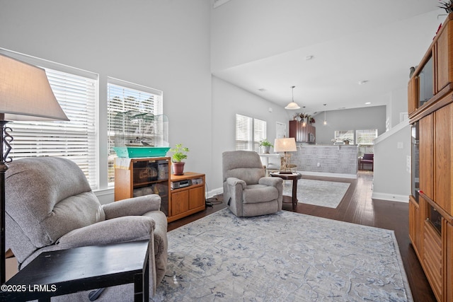 living room with a towering ceiling, baseboards, and dark wood finished floors