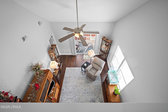 living room with dark wood-style floors, visible vents, and a ceiling fan