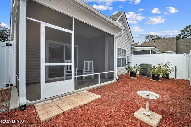 exterior space featuring central AC unit, fence, and a sunroom