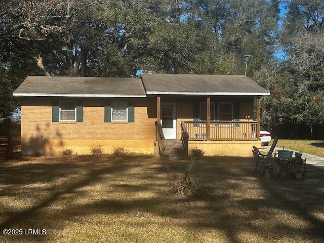 view of front of home with a porch, a front lawn, and brick siding