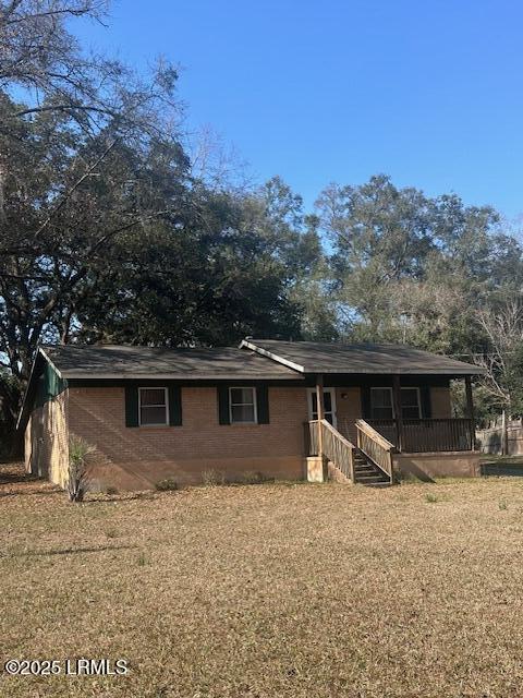 view of front of home featuring a front lawn, a porch, and brick siding