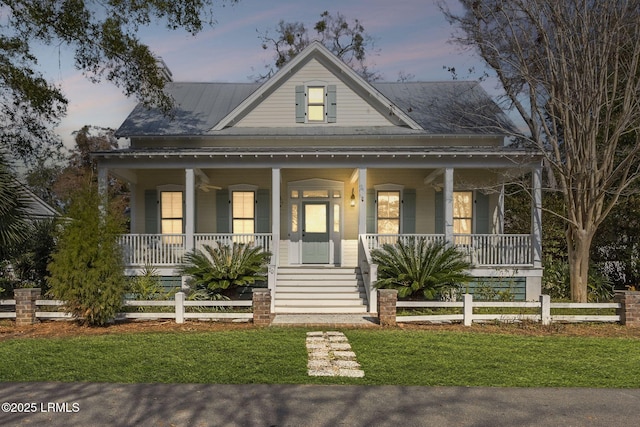 farmhouse inspired home with a fenced front yard, covered porch, and metal roof