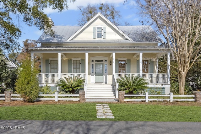 view of front of home featuring covered porch, a fenced front yard, and metal roof