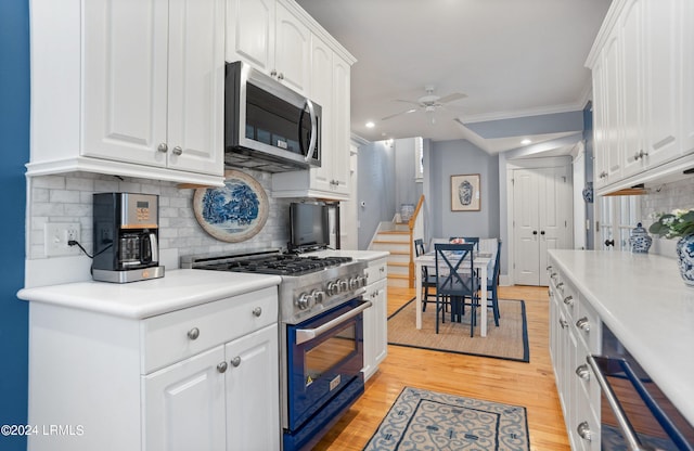 kitchen featuring white cabinetry, crown molding, ceiling fan, stainless steel appliances, and backsplash