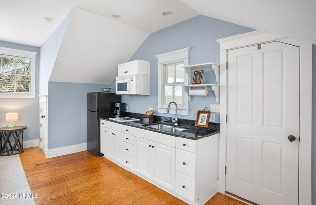 kitchen with vaulted ceiling, sink, white cabinets, and light hardwood / wood-style flooring