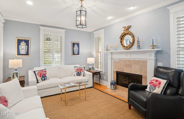 living room with a tiled fireplace, crown molding, and light wood-type flooring