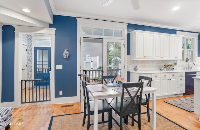 dining area featuring sink, ornamental molding, ceiling fan, and light wood-type flooring