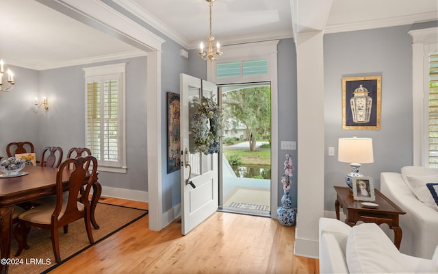 entrance foyer with a notable chandelier, crown molding, and light wood-type flooring