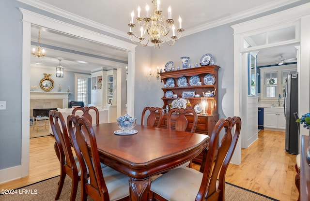 dining area featuring crown molding, ceiling fan with notable chandelier, a high end fireplace, and light hardwood / wood-style floors