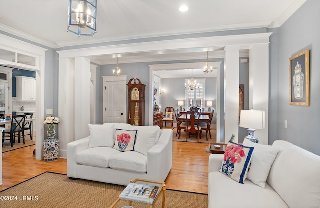 living room with a notable chandelier, crown molding, and light hardwood / wood-style flooring