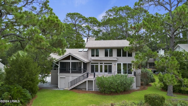 rear view of house featuring a lawn and a sunroom