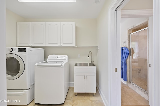 clothes washing area with sink, washer and clothes dryer, cabinets, and light tile patterned flooring