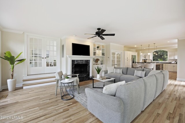 living room with ornamental molding, a premium fireplace, and light hardwood / wood-style floors