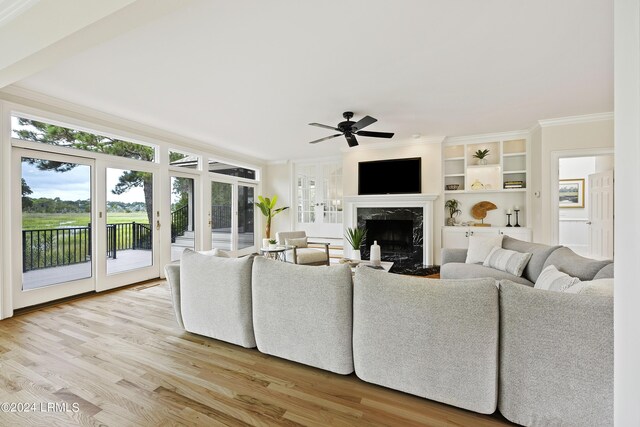 living room featuring crown molding, ceiling fan, a premium fireplace, and light hardwood / wood-style flooring