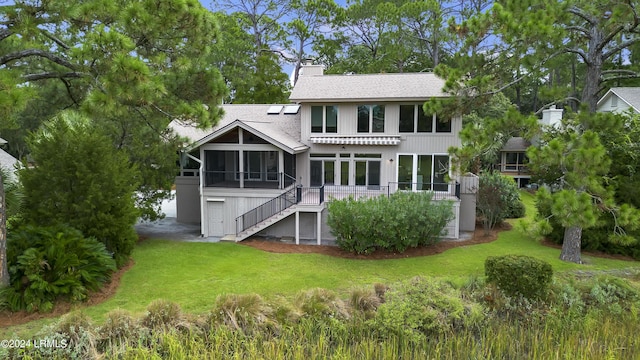 rear view of house featuring a lawn and a sunroom