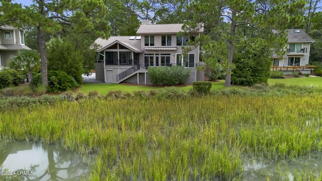 back of property with a sunroom and a water view