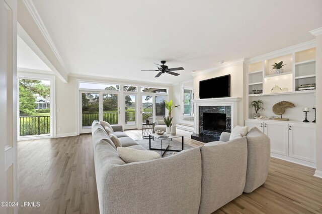 living room with ornamental molding, a high end fireplace, and light wood-type flooring