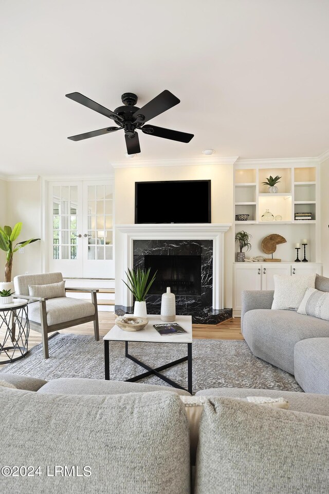 living room featuring crown molding, ceiling fan, a fireplace, and light wood-type flooring