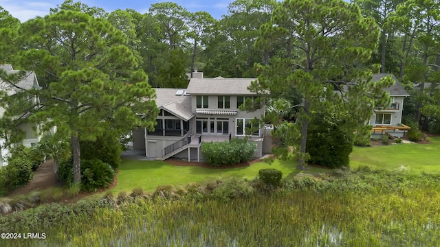 back of property with a sunroom and a lawn