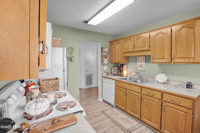 kitchen with sink, a textured ceiling, white appliances, and light hardwood / wood-style floors