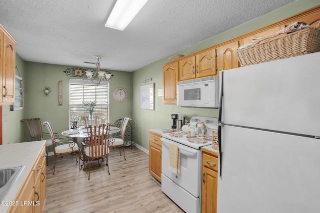 kitchen featuring pendant lighting, white appliances, a notable chandelier, a textured ceiling, and light hardwood / wood-style flooring