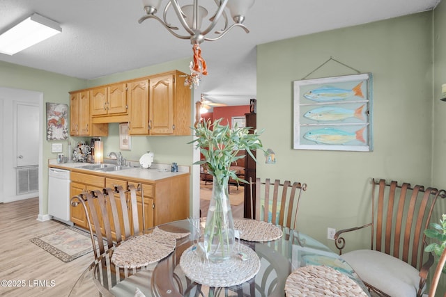 kitchen with sink, light wood-type flooring, a chandelier, white dishwasher, and a textured ceiling