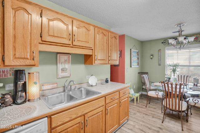 kitchen with dishwasher, sink, a notable chandelier, light hardwood / wood-style floors, and a textured ceiling