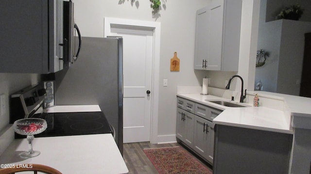 kitchen featuring a peninsula, dark wood-style flooring, a sink, light countertops, and electric range oven