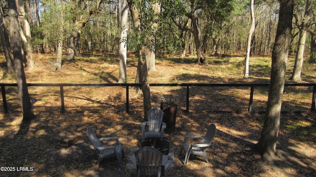 view of yard featuring fence, a wooded view, and a patio