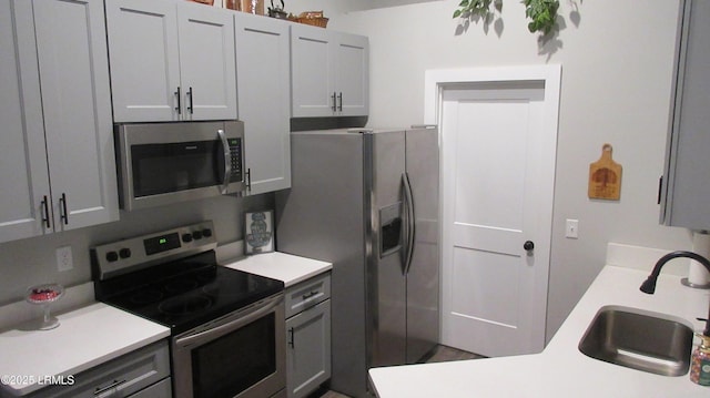 kitchen with stainless steel appliances, a sink, and light countertops