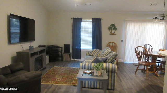 living area with baseboards, visible vents, and wood finished floors