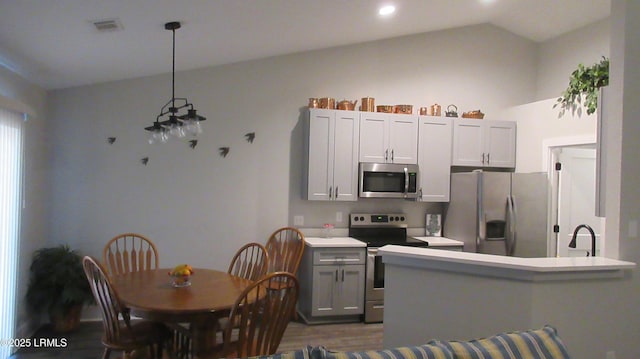 kitchen with lofted ceiling, light countertops, appliances with stainless steel finishes, and visible vents