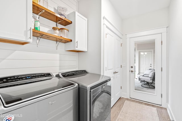 clothes washing area with light wood-type flooring, washing machine and dryer, and cabinet space