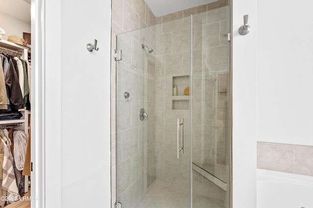 full bathroom featuring a shower stall, a spacious closet, and a bath