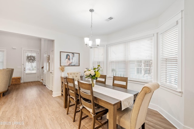 dining space with a notable chandelier, baseboards, visible vents, and light wood-style floors