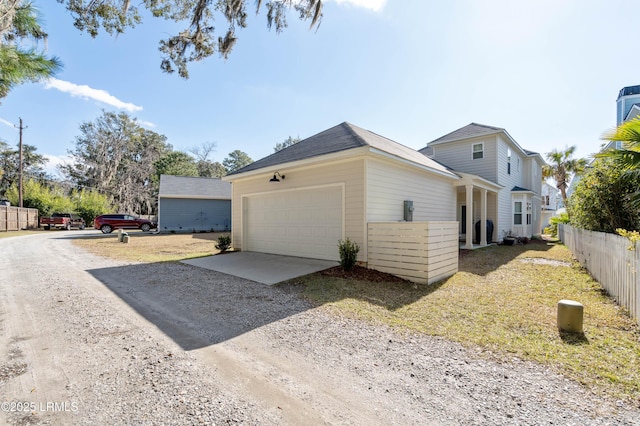 exterior space featuring driveway, an attached garage, and fence