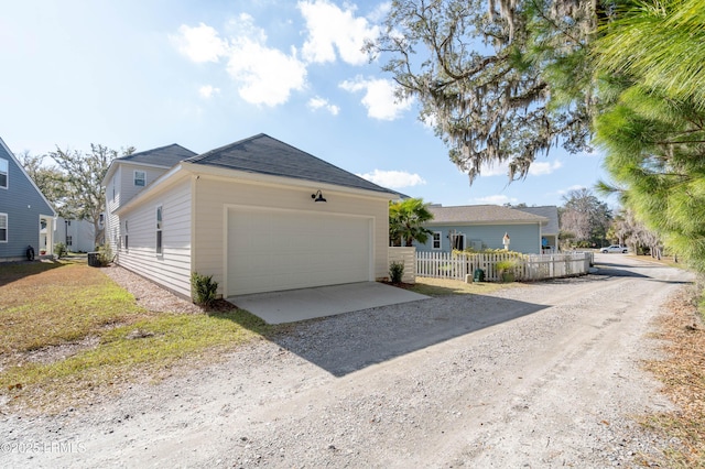 ranch-style home with dirt driveway, an attached garage, and fence