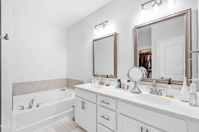 bathroom with a walk in closet, a garden tub, a sink, and double vanity