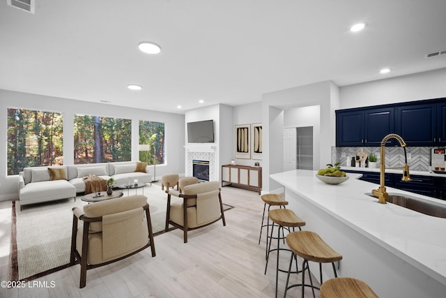 living area with recessed lighting, visible vents, light wood-style floors, and a tile fireplace