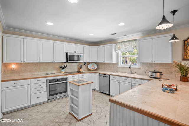 373 Pike Dr, Fripp Island, SC 29920 - kitchen with appliances with stainless steel finishes, white cabinets, ornamental molding, decorative backsplash, and decorative light fixtures